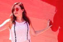 Load image into Gallery viewer, woman wearing subtle floral top against a red background
